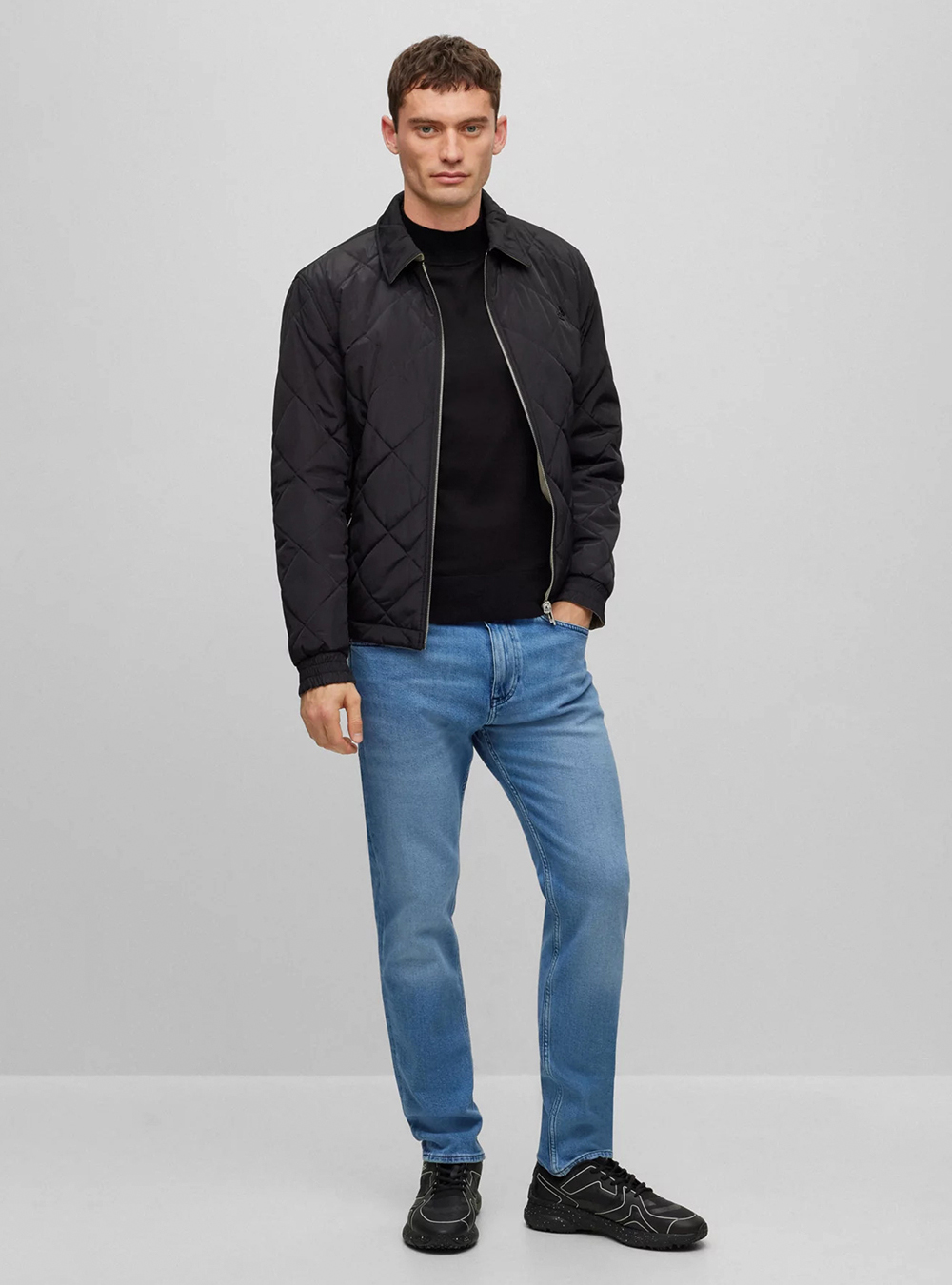 black quilted jacket and mock neck sweater paired with blue jeans 