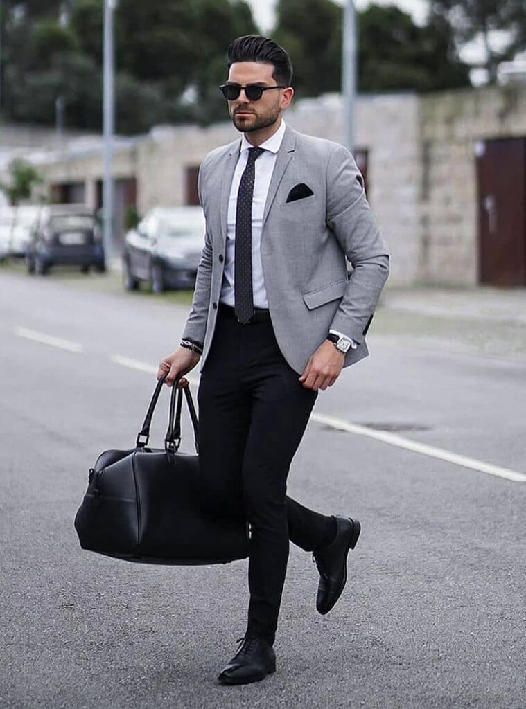 grey blazer. white shirt, black foulard tie, black pants, black oxford shoes