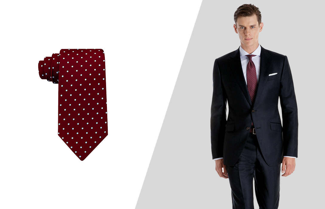 wearing a navy suit and a burgundy dotted tie